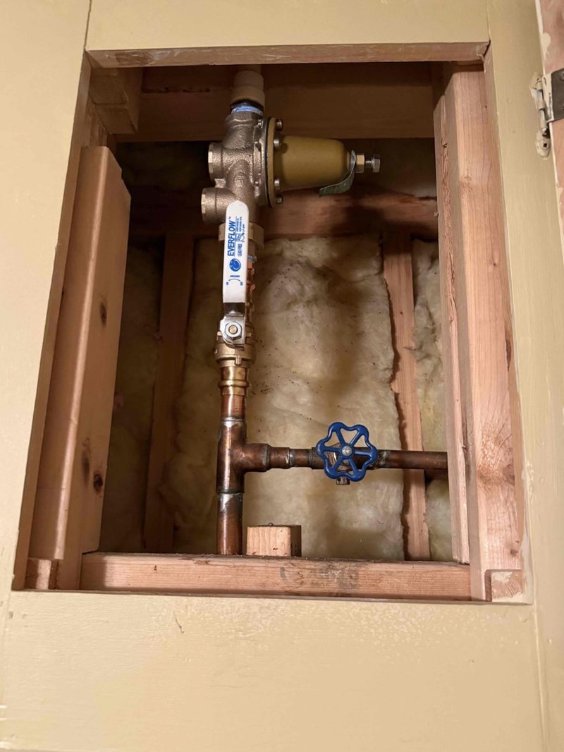 Pressure reducing valve and shut-off valve on copper pipe behind an access panel