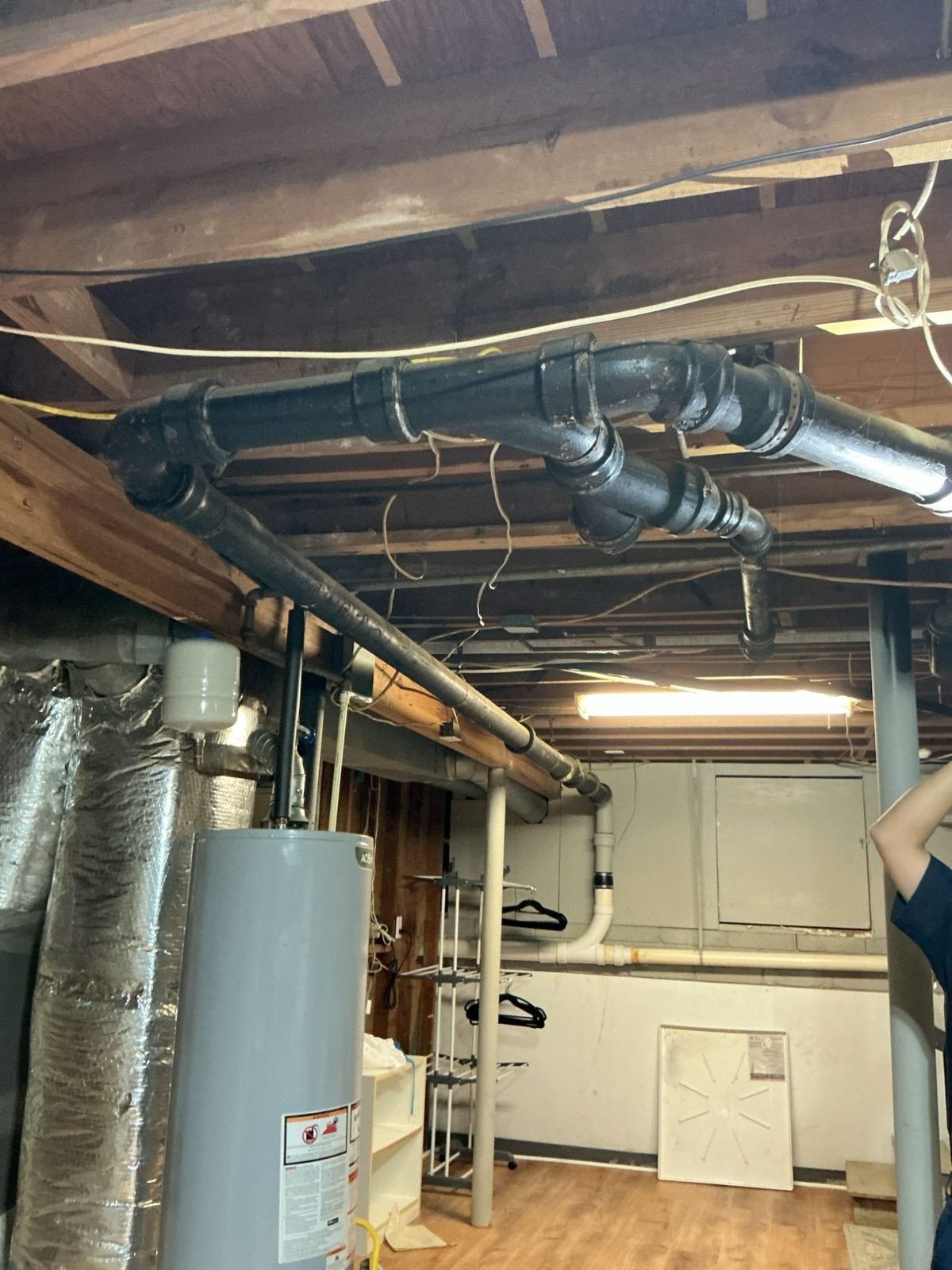 Before: old cast iron drain lines in a basement ceiling