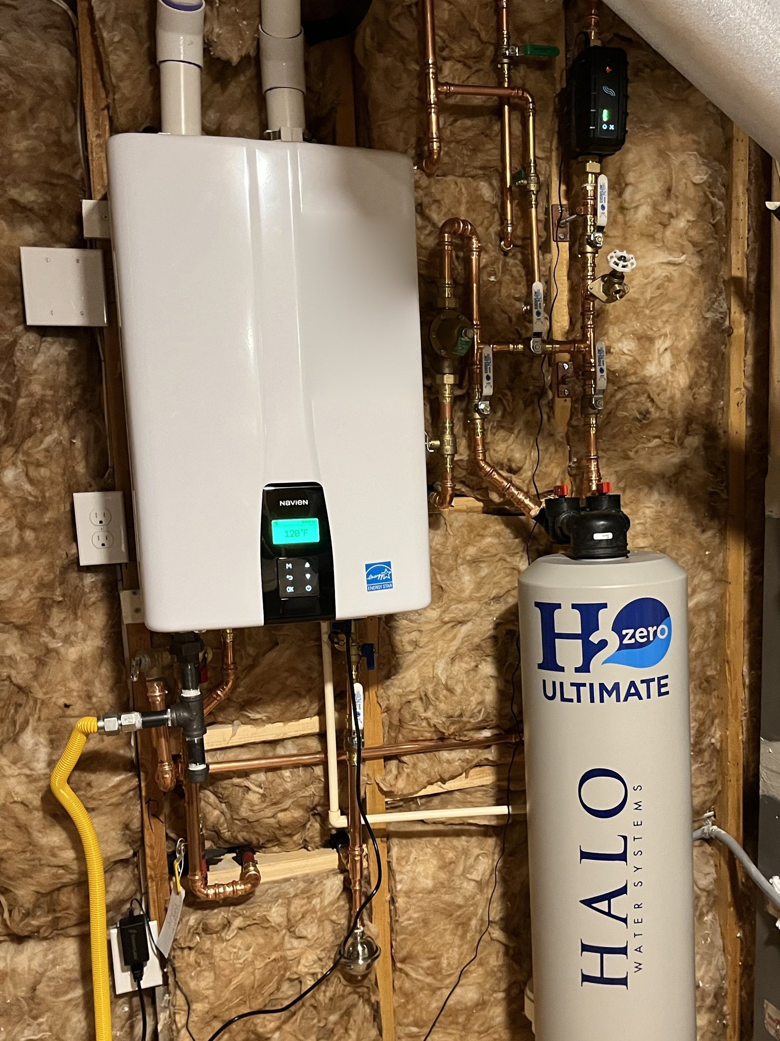 Wall-hung tankless water heater beside a whole-home water filtration tank