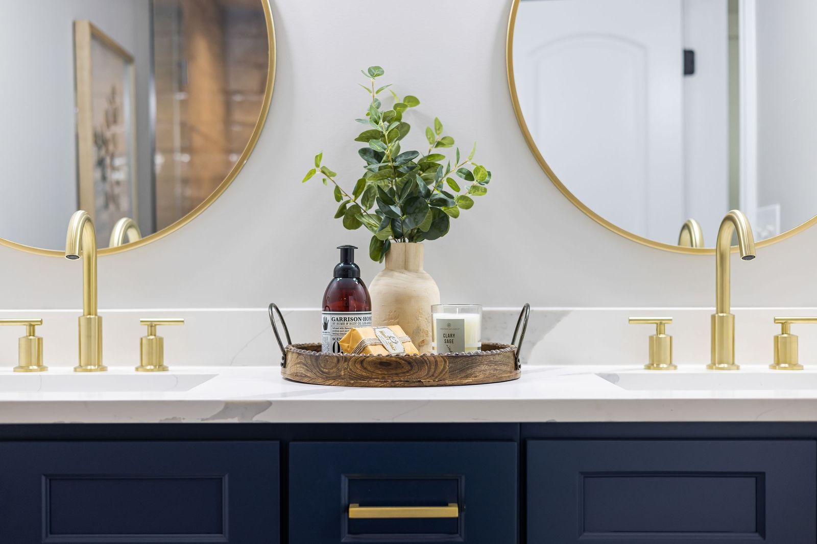 Bathroom vanity with gold faucets and navy cabinets